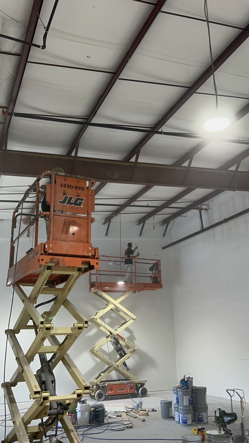 U Know Painting crew working on high commercial gym walls from elevated work platforms